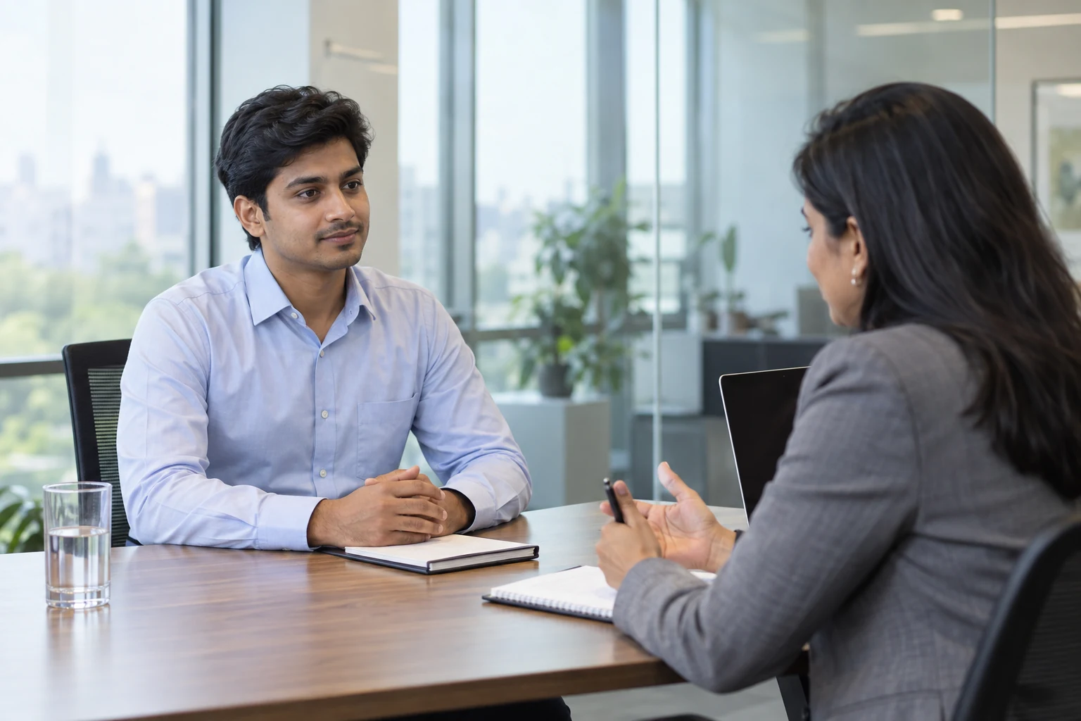 A candidate listening to a recruiter during an interview in a bright corporate office